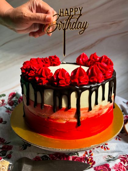 Adding the final touch. A "Happy Birthday" topper is placed on our red and black themed chocolate truffle cake.