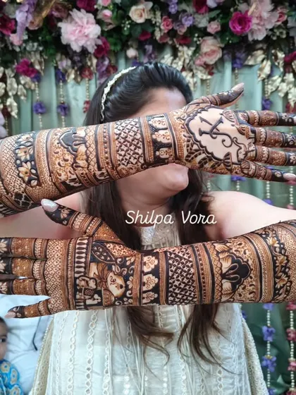 The bride displaying both of her fully adorned arms, a masterpiece of traditional patterns and personal touches.