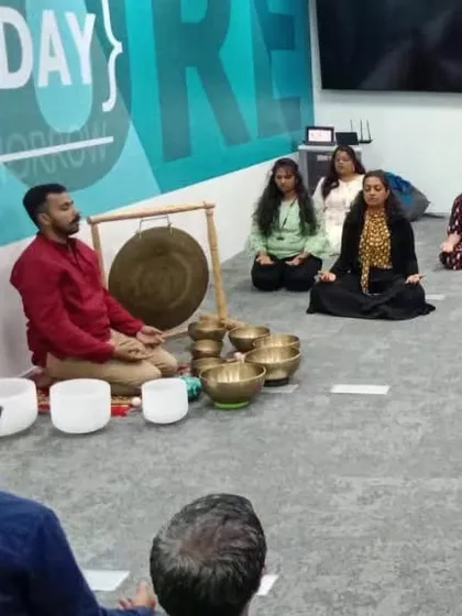 A corporate team begins their journey inward. Participants are seated in a comfortable meditative posture, preparing their minds for the immersive sound bath experience in their own office environment.