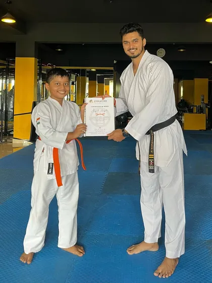 A young boy receives his orange belt certificate, a proud moment for him and his family.