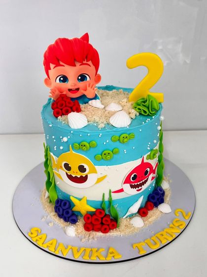 Making waves for a second birthday with this bright and bubbly Baby Shark-themed cake, complete with edible sand and favorite characters.