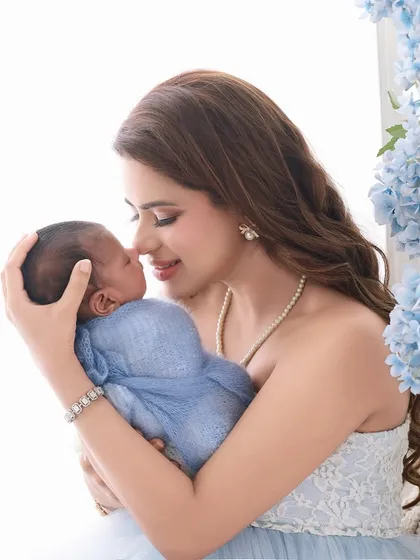This mother and newborn portrait incorporates soft blue hydrangeas to add a touch of color. The mother's gentle embrace and the baby's peaceful sleep make for a heartwarming image.