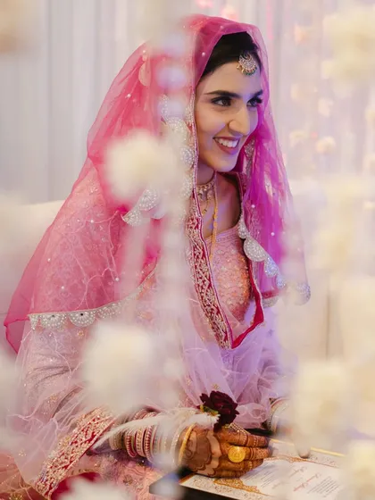 The bride's joyful smile during her "Qabool Hai" moment. Framed by flowers, this shot captures the happiness and beauty of her acceptance.