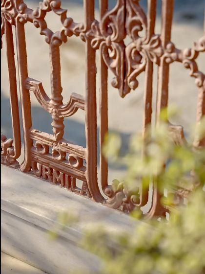 A detail of the original cast iron railing, where the name 'Urmila' is etched. This was Urmila Shastri, a freedom fighter and the home's previous owner, whose feminine, resilient spirit is still felt in the architecture.