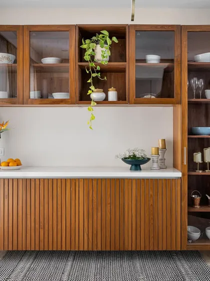 This large, floating crockery unit features fluted wood paneling on the base and glass-fronted upper cabinets, combining texture and transparency.