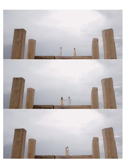 A series of three shots showing a couple meeting and embracing on a stone structure, framed by large pillars against the sky.