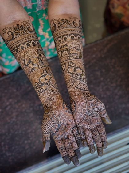 The full view of the arms, showcasing a traditional design filled with peacocks, elephants, and floral bands.