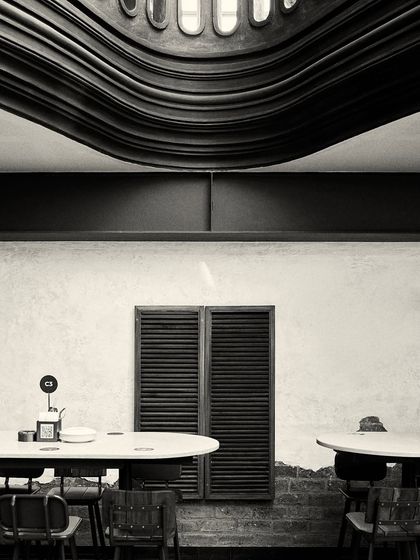 The underside of the curved balcony creates a unique, wave-like ceiling feature over a dining area.