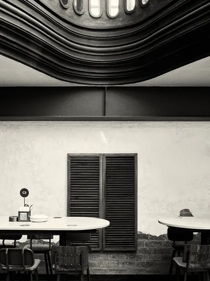 The underside of the curved balcony creates a unique, wave-like ceiling feature over a dining area.
