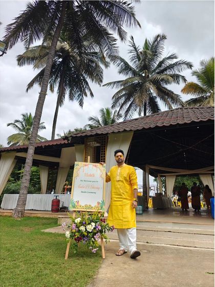 Bringing the sunshine with a bright yellow kurta for a beautiful outdoor wedding event. The vibe is set with coconut trees and a clear sky, perfect for some daytime grooves.