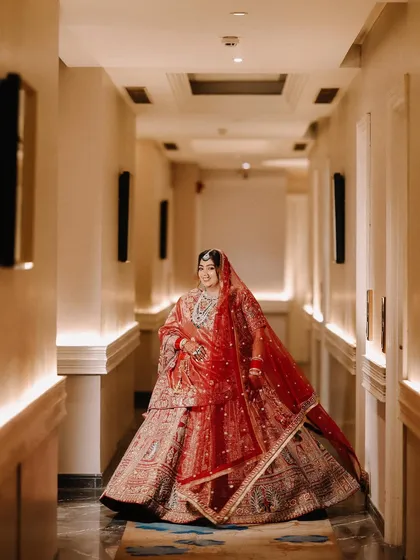 Using the leading lines of the hotel corridor, I framed the bride to create a powerful and elegant portrait. Her red lehenga fills the frame, making her the undeniable center of attention.