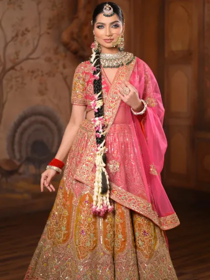 This bride is a vision in vibrant pink and orange. The makeup is fresh and luminous, with a focus on glowing skin and bright eyes to match the colorful, festive lehenga.