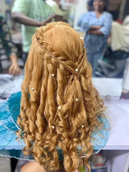 A beautiful half up, half down hairstyle with soft curls and braids, created by a student. This romantic look is perfect for an engagement or pre wedding shoot.