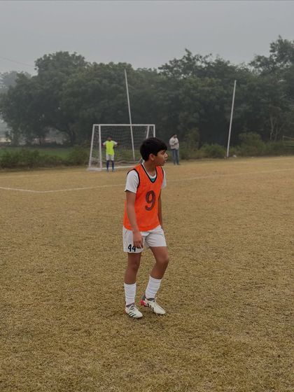 A U-14 player wearing an orange bib, focused during a practice game. These matches are crucial for applying learned skills.
