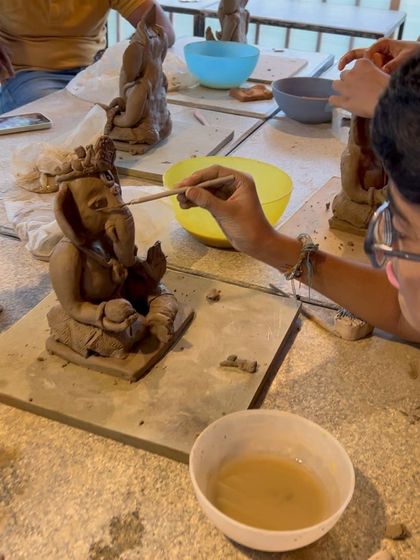 A student carefully uses a tool to add fine details to the crown of their Ganesha idol. This is where the personality of each Bappa starts to shine.