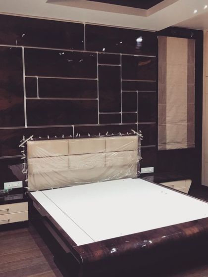 In this luxury bungalow, the master bedroom features a high-gloss, dark wood panel behind the bed with geometric inlays. The design is sleek, modern, and sophisticated.