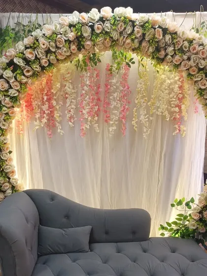 A beautiful floral ring decoration for a Parna ceremony. The setup includes a white curtain backdrop, hanging wisteria, and a comfortable chaise lounge.