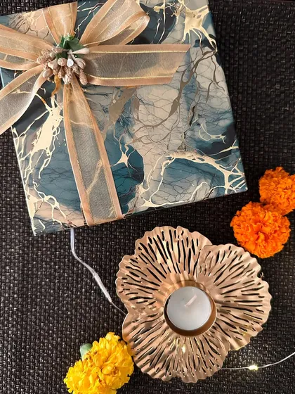 A golden floral T-light holder paired with a beautifully wrapped gift box. This small but elegant piece is perfect for adding a festive touch to any space.