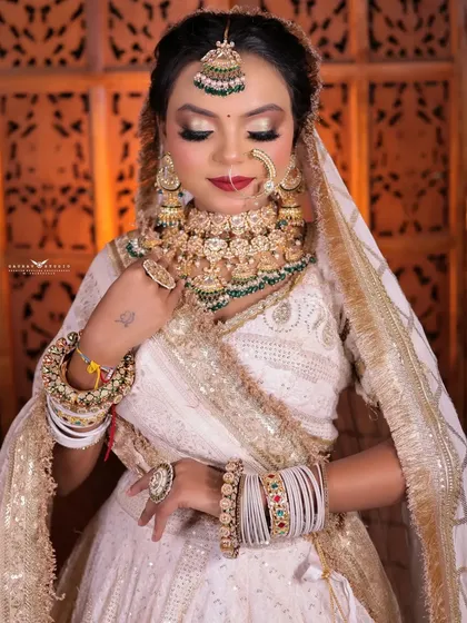 A serene portrait with the bride's eyes closed, focusing on the gold and white tones of her makeup and jewelry.