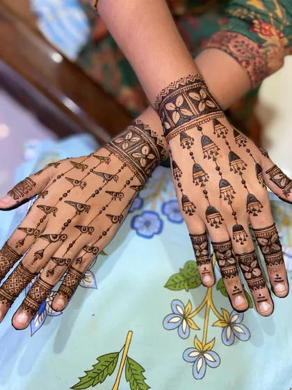 An elegant and modern mehandi design perfect for guests. This pattern features delicate hanging jhumkas (earrings) and bird motifs, offering a stylish and less dense alternative to traditional heavy designs.