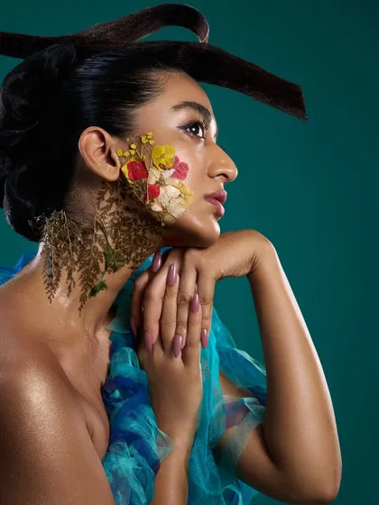 A profile view from the 'Roots' editorial, highlighting the sculptural hair and the organic texture of the floral makeup.