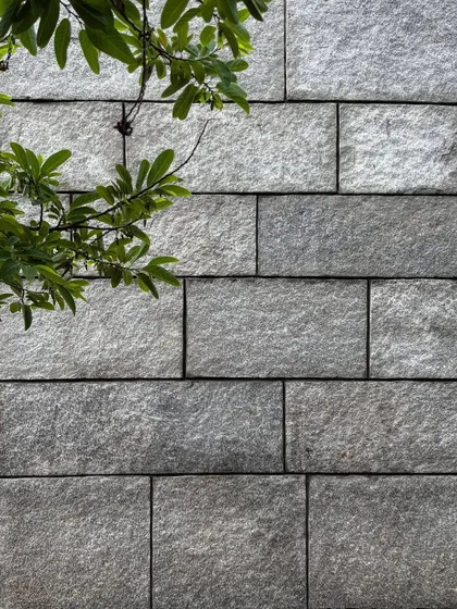 A sample of a granite wall, showing the precise joinery and textured finish of the stone. We work closely with stonemasons to select and craft each block, celebrating the natural beauty of the material.