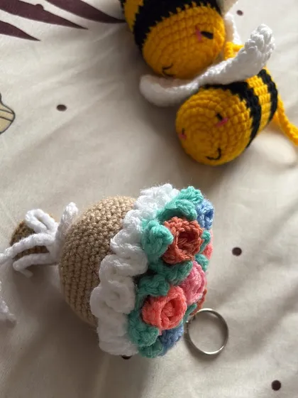Another view of the crochet bees and flower bucket keychain, showing the detail on the back of the items.