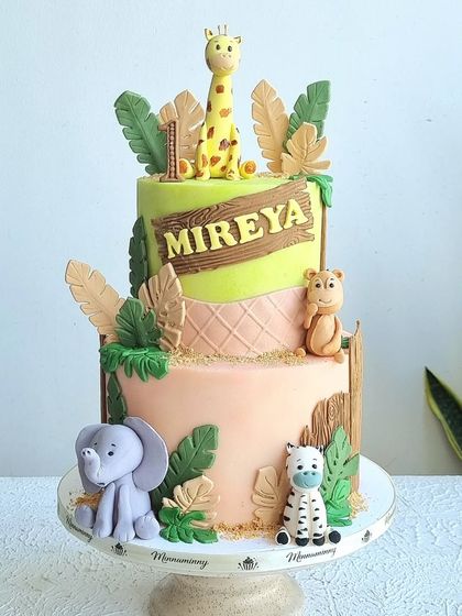 A full view of the two-tiered safari cake on its stand.