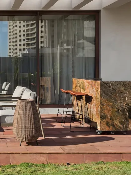 A movable bar crafted from a single piece of stone adds a functional and sculptural element to this terrace. This space is designed to be a serene escape from the city, surrounded by a lush private garden.