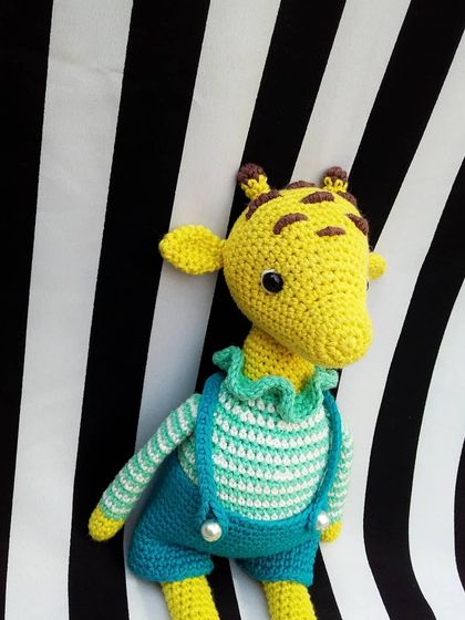 A close-up of the giraffe doll, showing the details on his face and the little pearl buttons on his overalls.