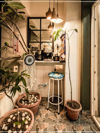 A bohemian-style balcony corner with a coffee bar, dreamcatcher, and potted plants, perfect for a quiet pause.