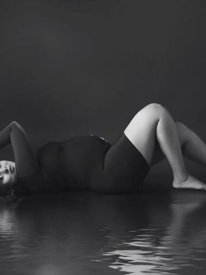 An artistic black and white portrait with a water reflection, creating a moody, high-fashion look.