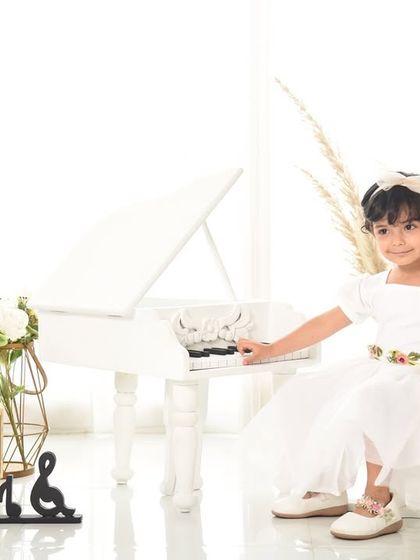 A classic portrait for a third birthday. The simple white piano and natural pampas grass create an elegant and timeless feel.
