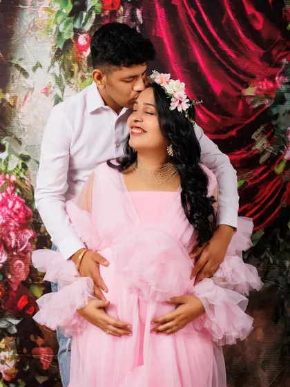 A gentle kiss on the forehead is a classic expression of love and protection. For this shot, the couple is framed against a beautiful floral backdrop, with her in a lovely pink gown. It’s these intimate gestures that create truly timeless and emotional maternity portraits.