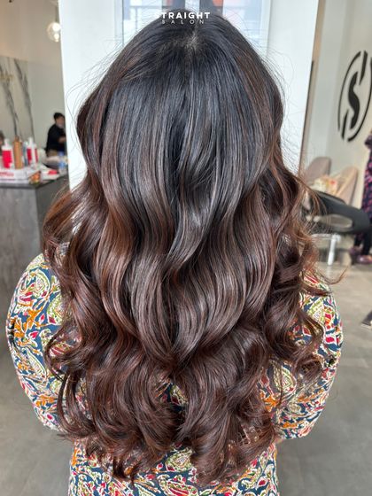 Volume, shine, and confidence. This look showcases a deep brunette base with subtle highlights, styled into classic, glamorous waves.