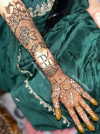 A full view of Kulsum's bridal henna, showcasing the personalized initials and the rich, dense patterns covering her arm.