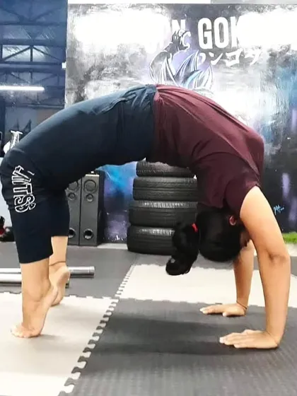 A student holds a strong wheel pose (Chakrasana) on their toes, which increases the intensity of the backbend and engages the leg muscles more deeply.