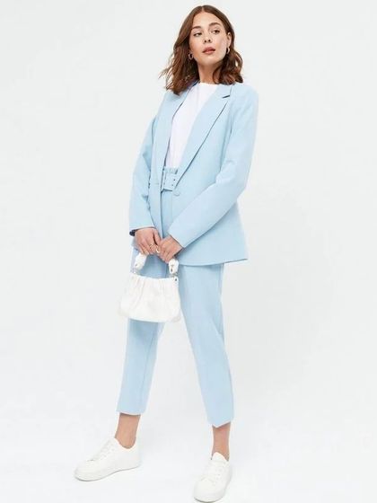 This light blue power suit offers a softer, more relaxed take on formal wear. It's styled here with sneakers for a chic, casual look.