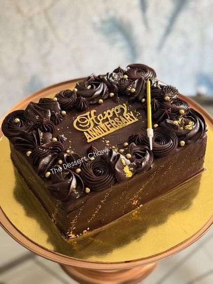An elegant square chocolate truffle cake for an anniversary celebration. I decorated it with rich chocolate rosettes, gold dust, and a "Happy Anniversary" topper to make it extra special.