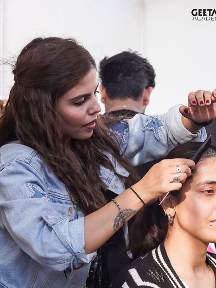 A student focuses on perfecting a hairstyle backstage. This kind of high-pressure environment is the best training for a real-world career.