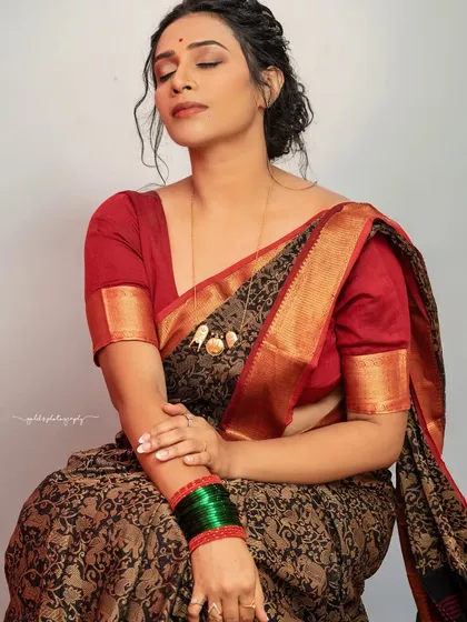 A seated portrait with a serene and contemplative mood. The focus is on the texture of the saree and the bride's relaxed posture.