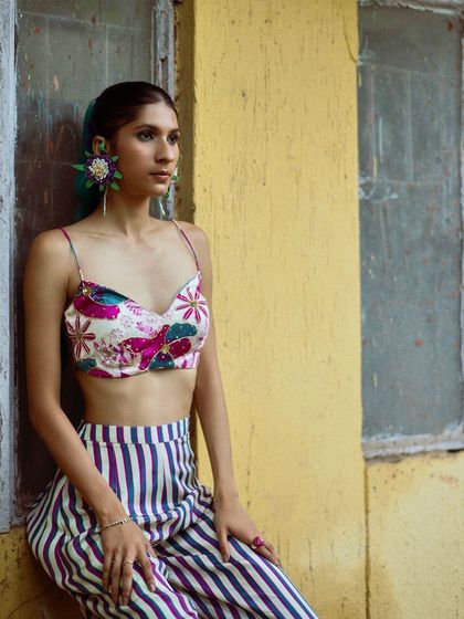 A close-up from a street style shoot, focusing on the bold floral earrings and the texture of the printed top.