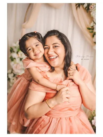 A joyful mother and daughter sharing a heartfelt hug in the studio. This portrait, with its soft floral background, captures the beautiful bond between them, perfect for a Mother's Day or family session.
