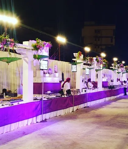 A grand setup for a large-scale event, featuring a long line of counters with elegant white and purple decor. I can cater to events of any size without compromising on style.