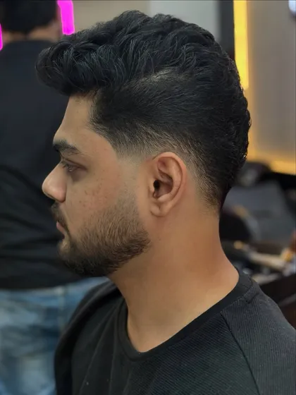 A side profile view showcasing the precision of the temple fade and the crisp line of the beard. Every detail matters when it comes to a sharp men's haircut.