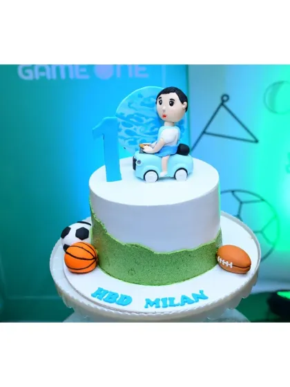 The cake for the "Game On" sports-themed party. It features a figurine of the birthday boy and is surrounded by mini edible sports balls.