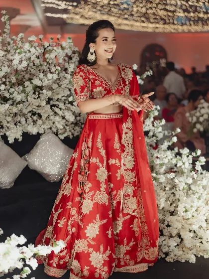 Here is Tessa, radiant and happy on her big day. This full view shows how minimal makeup creates a powerful impact, allowing the bride's joy and the beauty of her traditional red lehenga to take center stage.