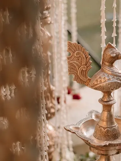A close-up of a traditional brass 'Samai' or oil lamp, an auspicious element in Indian ceremonies.