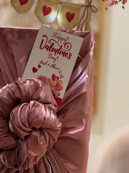 A gift wrapped in dusty rose fabric using the Furoshiki technique, complete with a personalized Valentine's Day card.