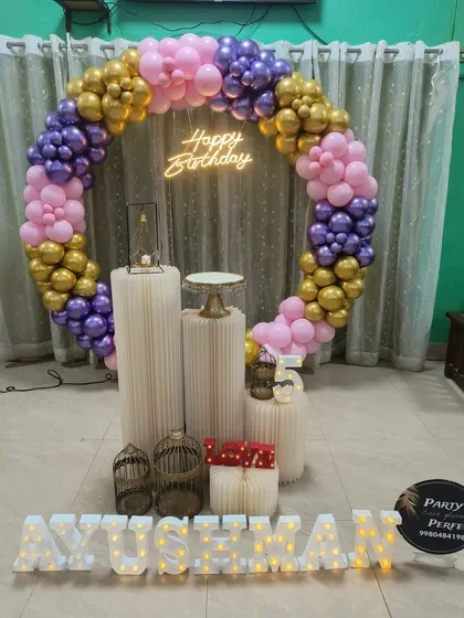 A vibrant and fun color combination of purple, pink, and gold for Ayushman's 5th birthday. The full balloon ring, neon sign, and light-up name make for a cheerful and exciting party atmosphere.